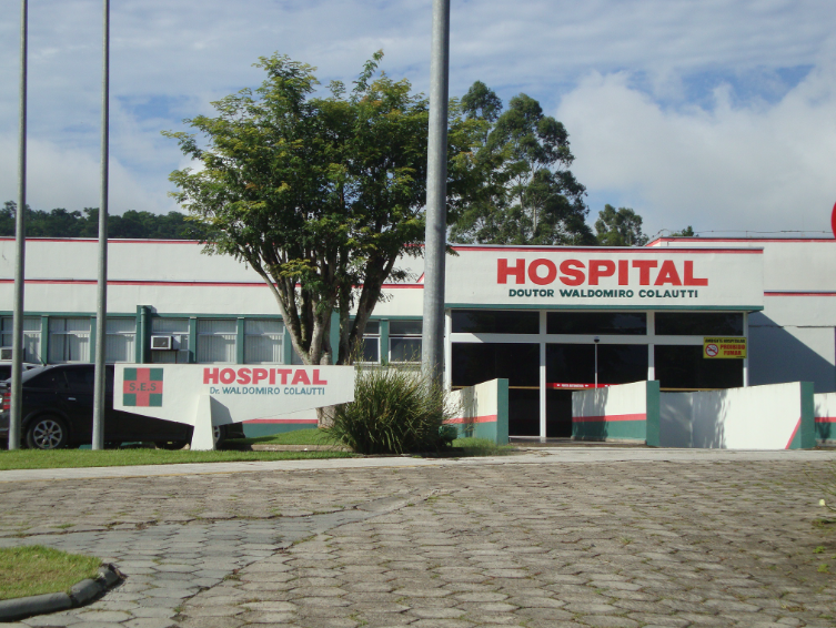 Fachada do Hospital Doutor Waldomiro Colautti, com letreiros em vermelho e entrada principal cercada por jardins.