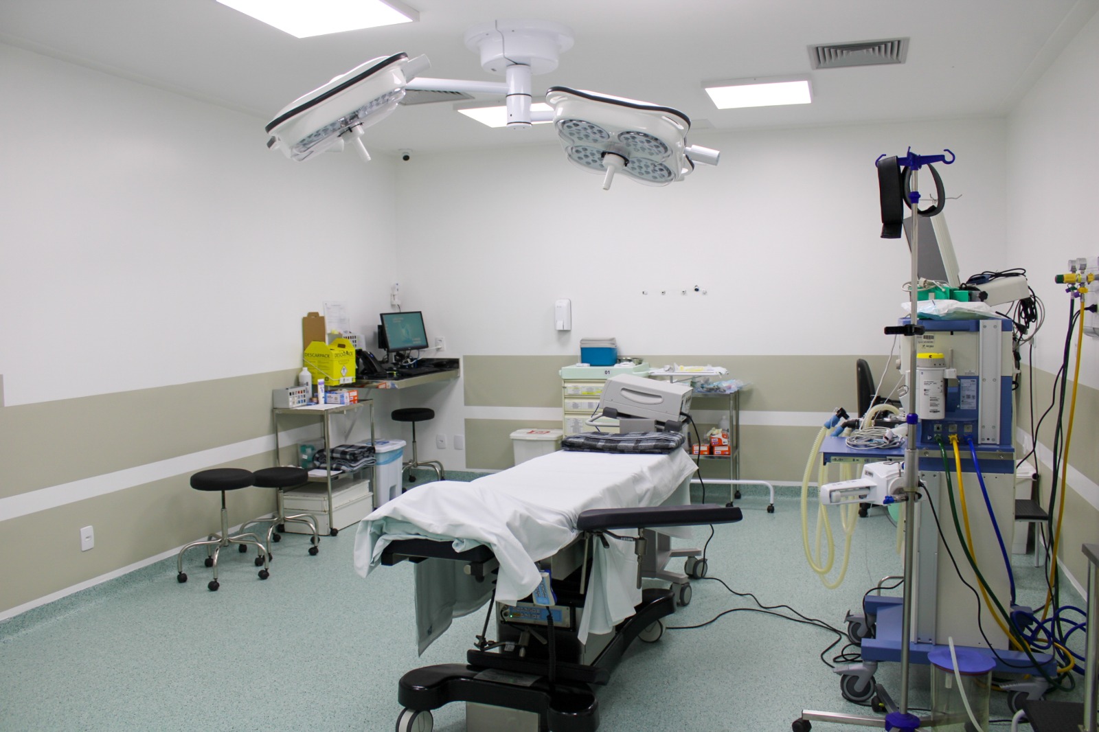 Sala cirúrgica moderna e equipada no Hospital Santo Antônio, com mesa de cirurgia, focos cirúrgicos no teto, monitores e equipamentos de suporte anestésico.