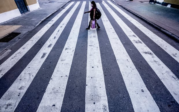 Mulher utilizando faixa de pedestres corretamente, representando mobilidade urbana segura durante medidas de prevenção em Santa Catarina.
