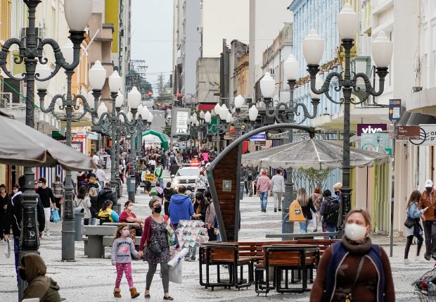 Rua movimentada de Florianópolis com população usando máscaras de proteção, em cena do cotidiano urbano durante pandemia, após decisão do COES de não decretar lockdown no estado.