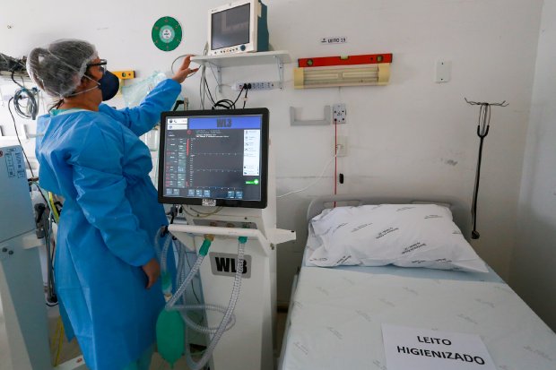 Profissional da saúde manipulando monitores em leito