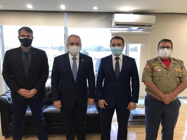 Governador Carlos Moisés e três autoridades posam para foto em sala de reuniões, com janela e aparelho de ar-condicionado visíveis ao fundo.