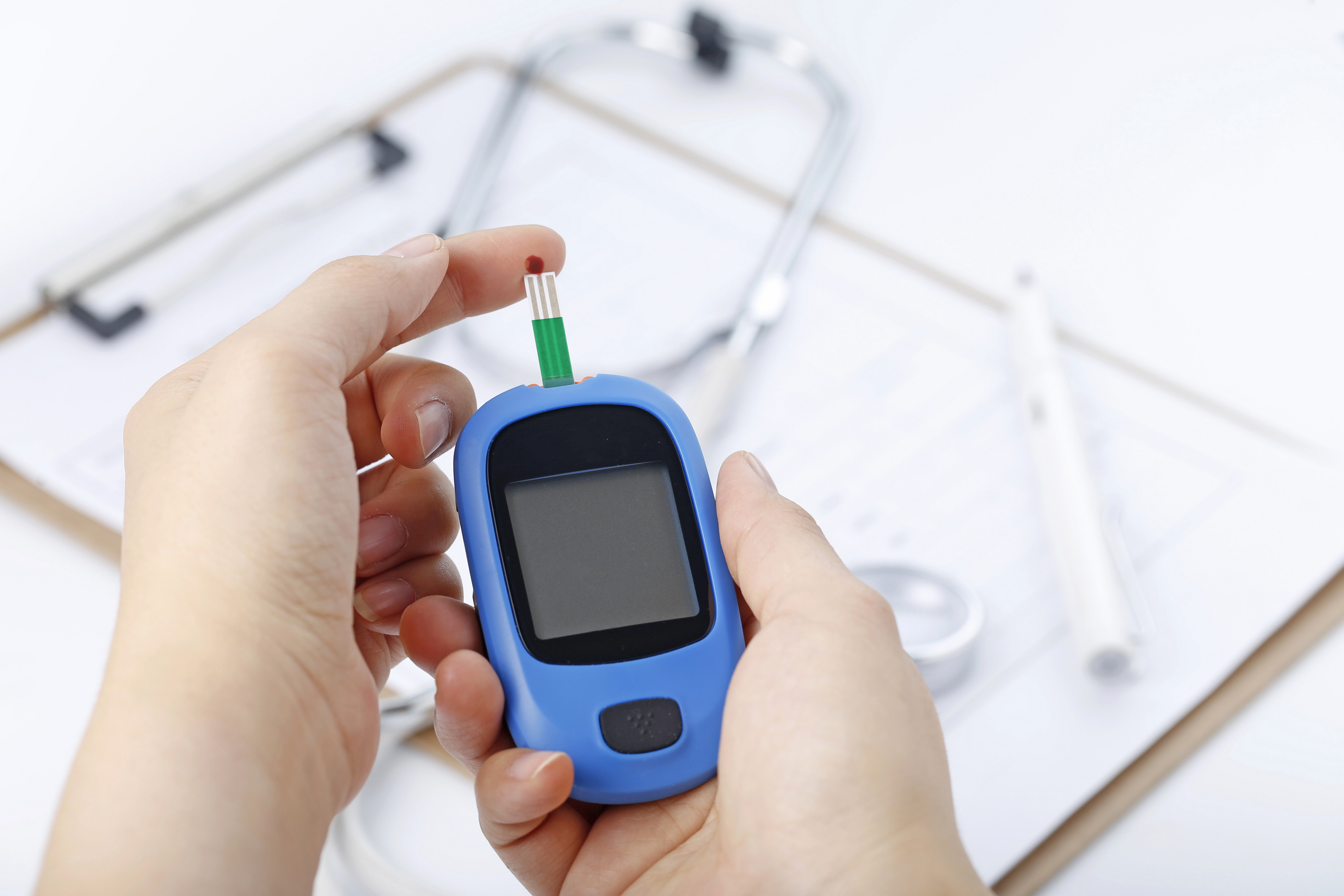 hand-holding-a-blood-glucose-meter-measuring-blood-sugar-the-background-is-a-stethoscope-and-chart-file.jpg